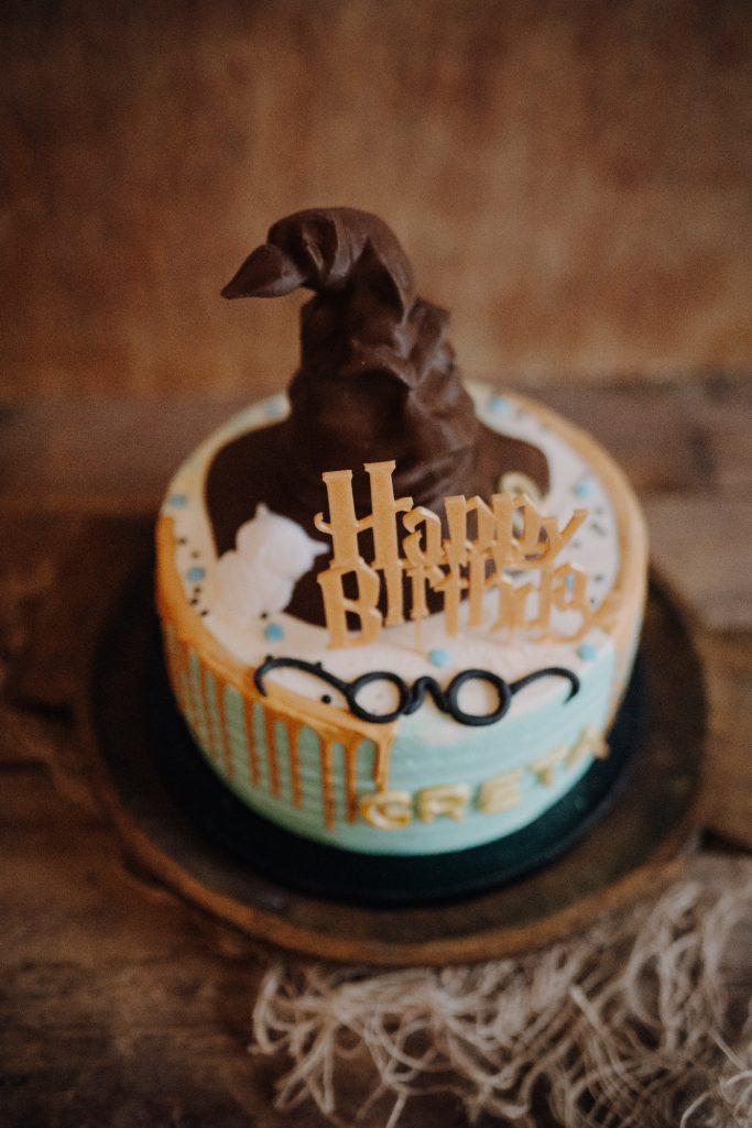 Torte mit Zauberhut, Brille und dem Text "Happy Birthday" in festlichen Farben.