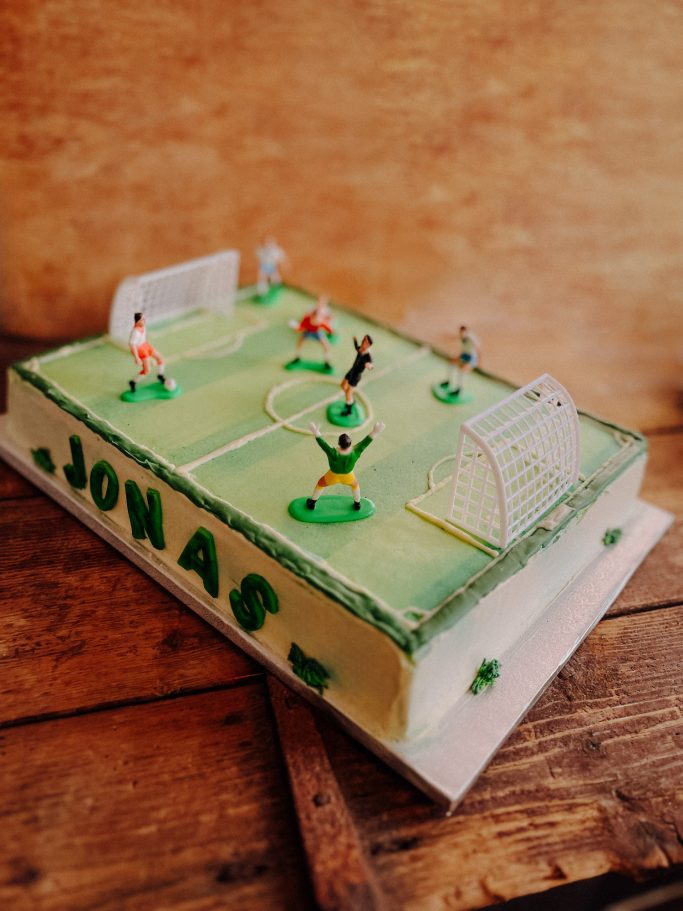 Fußballkuchen mit Spielern auf dem Spielfeld und Toren, beschriftet mit "JONAS".