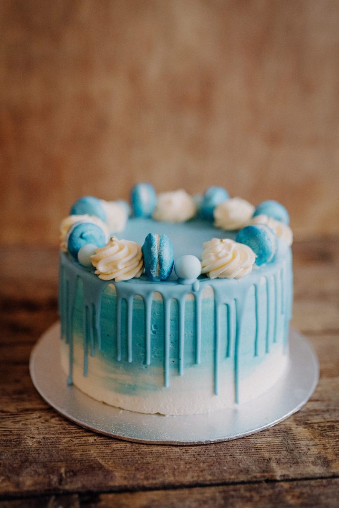 Torte mit blauer Glasur, weißen Rosetten und Dekoration in Blau.