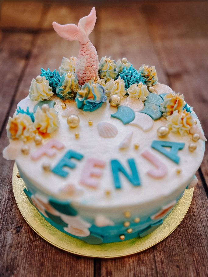Unterwasser-Themen-Torte mit einem Meerjungfrau-Schwanz und bunten Dekorationen.