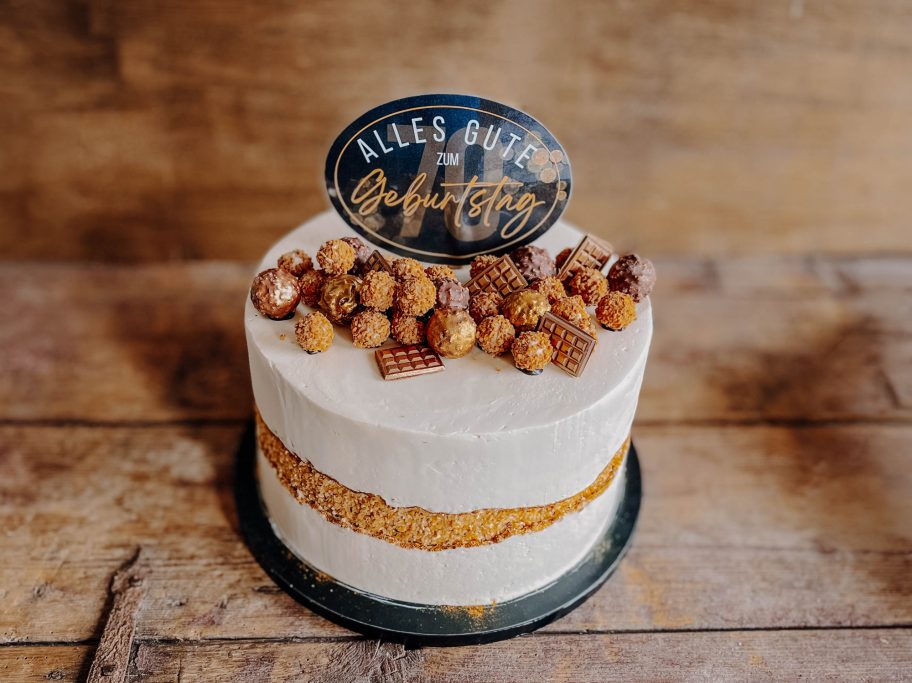 Torte mit Nüssen, Schokoladendekoration und einem Schild mit der Aufschrift "Alles Gute".