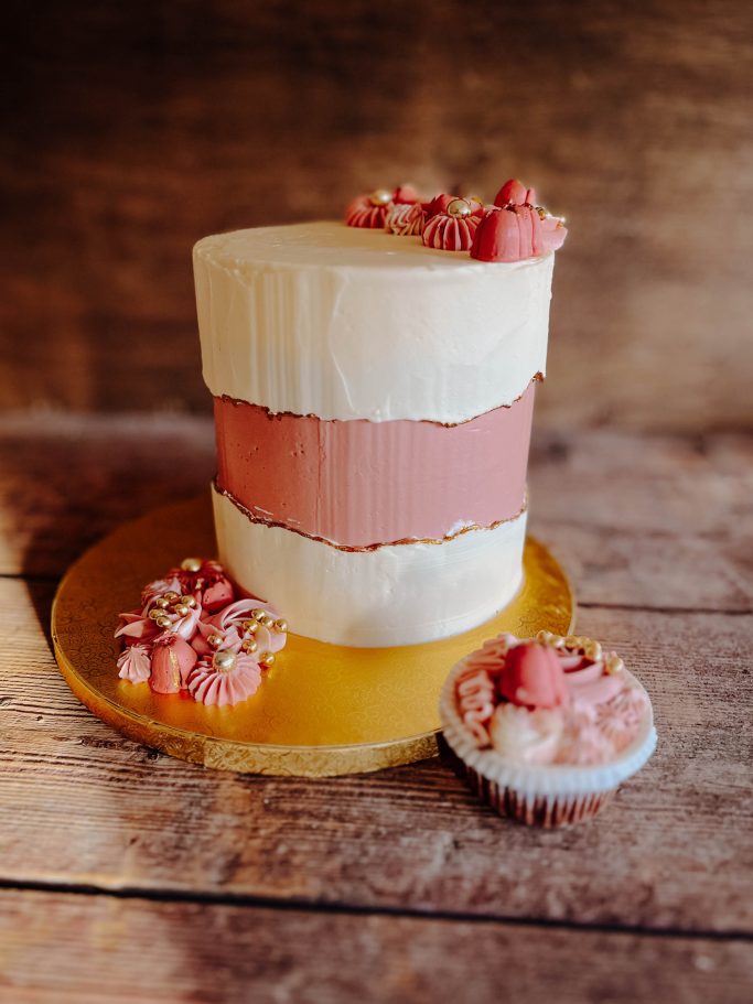 Hochzeitstorte in Rosa- und Cremetönen, dekoriert mit frischen Beeren und Sahne.