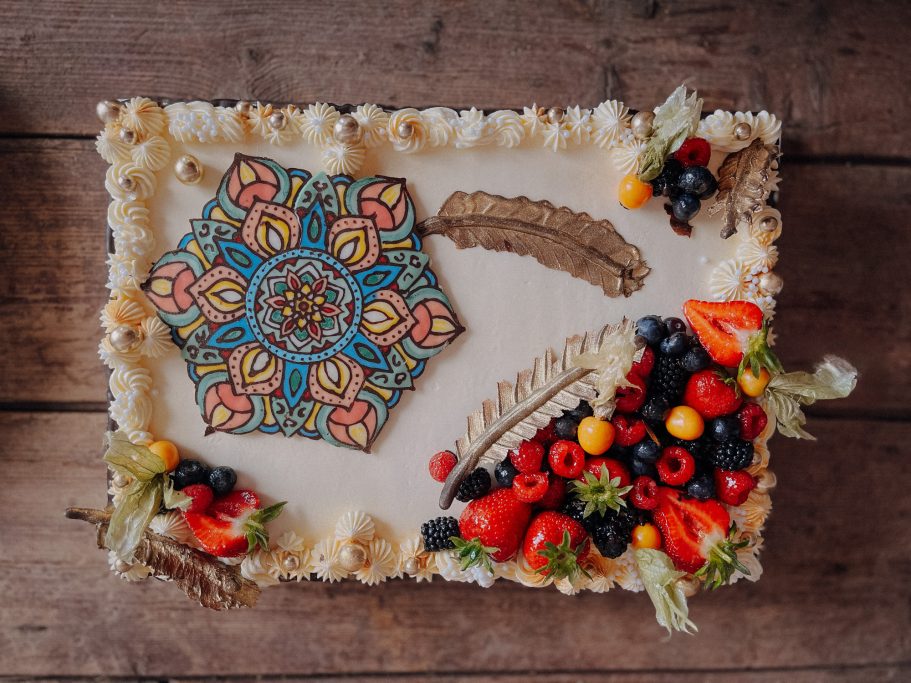 Bunte Torte mit einer dekorativen Musterzeichnung und frischen Früchten.