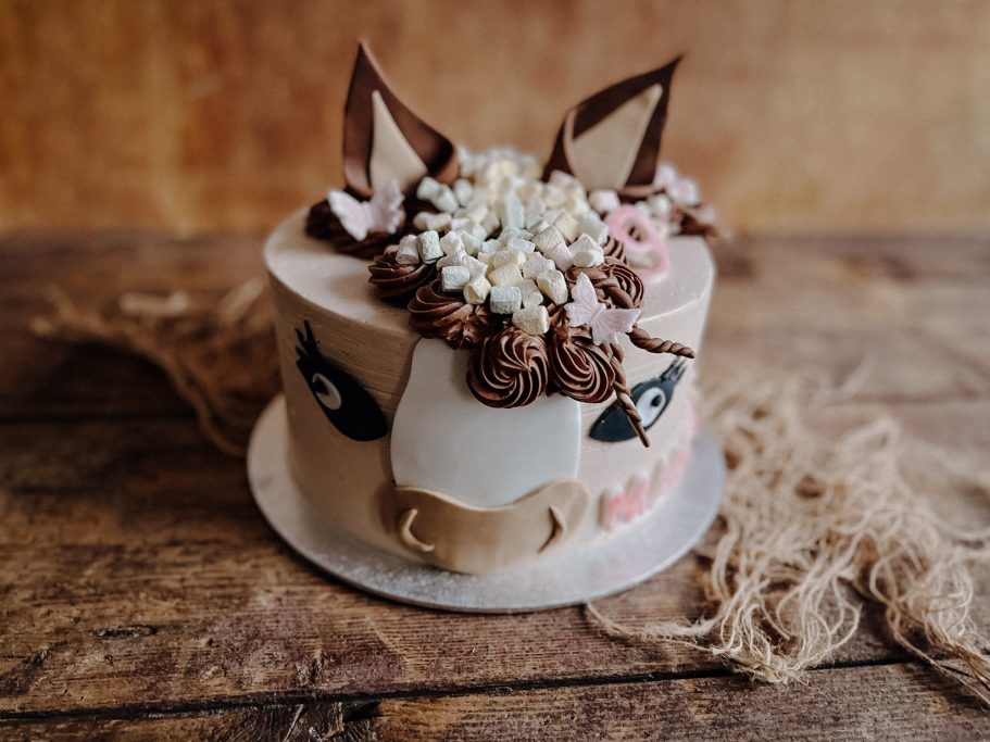 Runder Kuchen mit einer Tiermotivanordnung aus Schokolade und Blumen.