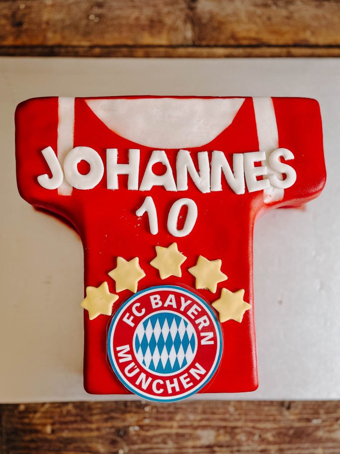 Tortendekoration in Form eines Fußballtrikots mit Aufschrift "Johannes 10" und Bayern-Logo.