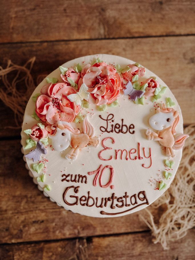 Torte dekoriert mit Blumen und Schmetterlingen, beschriftet für Emelys 10. Geburtstag.