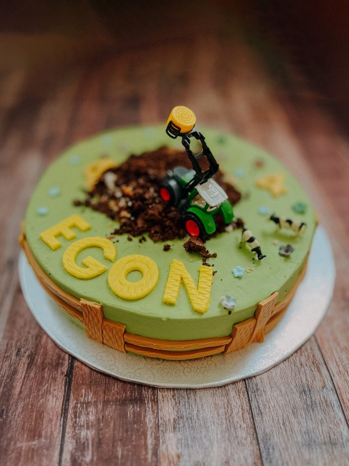 Geburtstagskuchen mit grünem Fondant, einer Rasenmäherfigur und dem Namen "EGON".