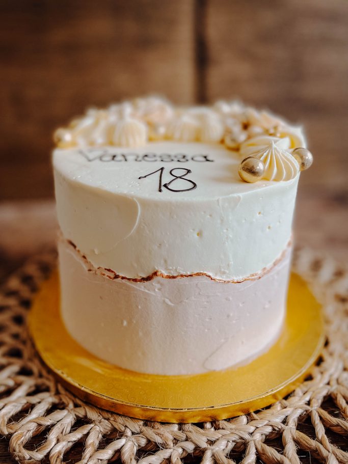 Torte mit zwei Schichten, dekoriert mit Sahnerosen und der Aufschrift "18".
