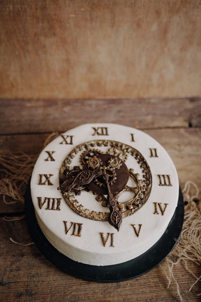 Torte in Form einer Uhr, mit römischen Ziffern und filigranem Uhrwerk.