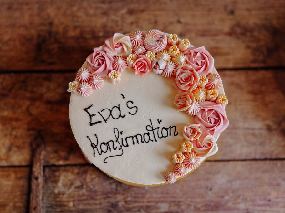 Kuchen mit rosa Blüten und der Aufschrift "Eva's Konfirmation".