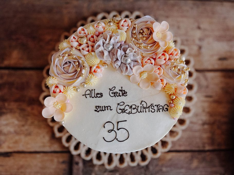 Runder Kuchen mit bunten Blumen und der Aufschrift „Für die beste Mama 35“.