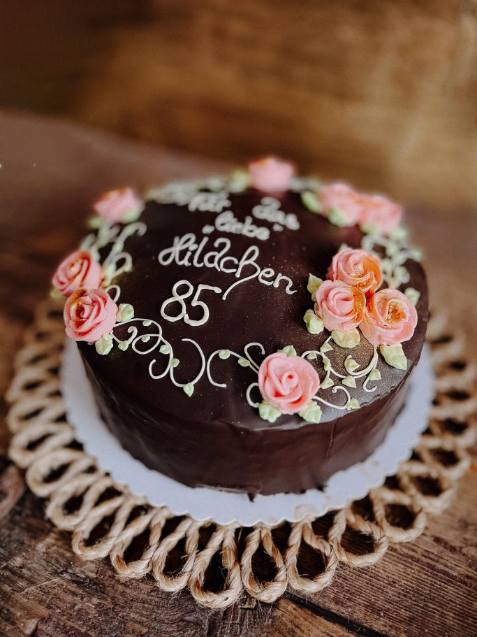 Schokoladenkuchen mit bunten Rosen und der Beschriftung "85".