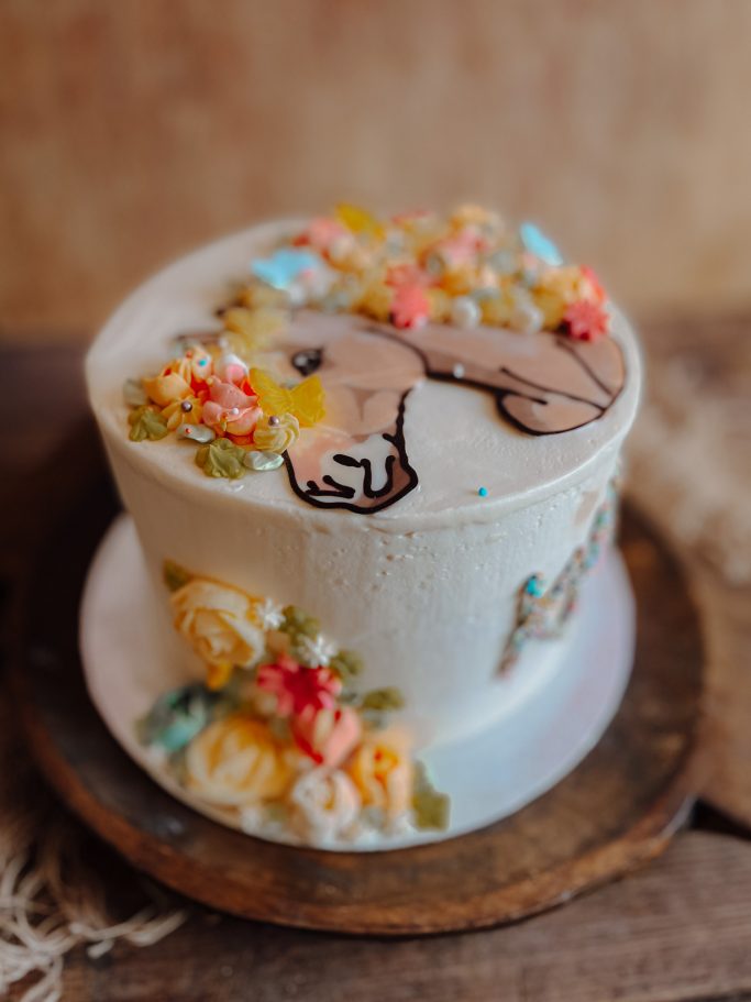Torte mit Pferdemotiv und bunten Blumenverzierungen auf Holzunterlage.