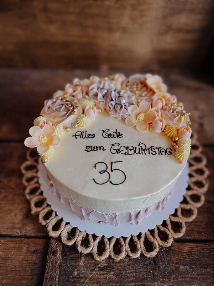 Torte mit Blumenverzierung und der Aufschrift „Für dich zum Geburtstag 35“.