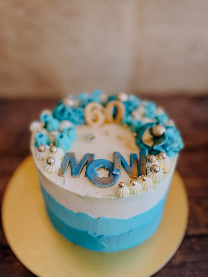 Geburtstagskuchen mit türkisfarbenem Zuckerguss und der Aufschrift "60 MONI".